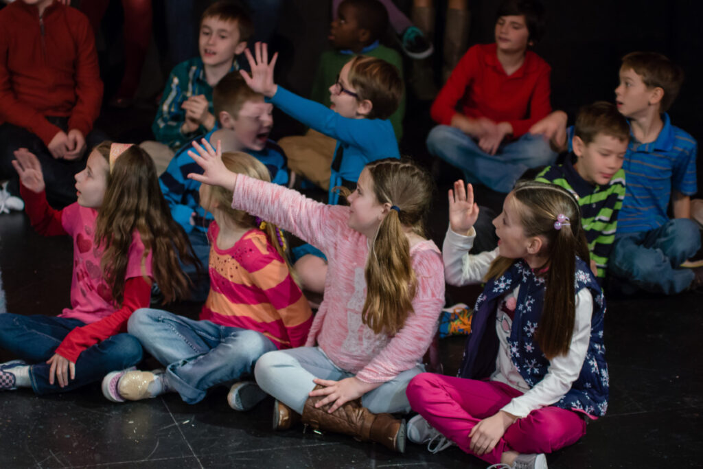 Students sit with their hands raised